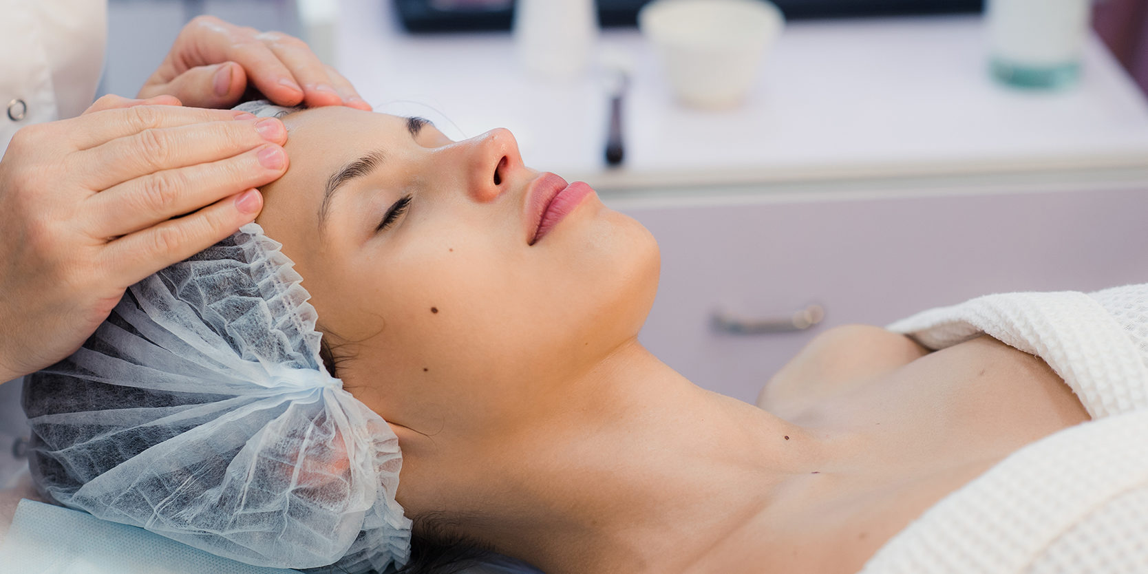 Beautiful young woman relaxing with face massage at beauty spa.