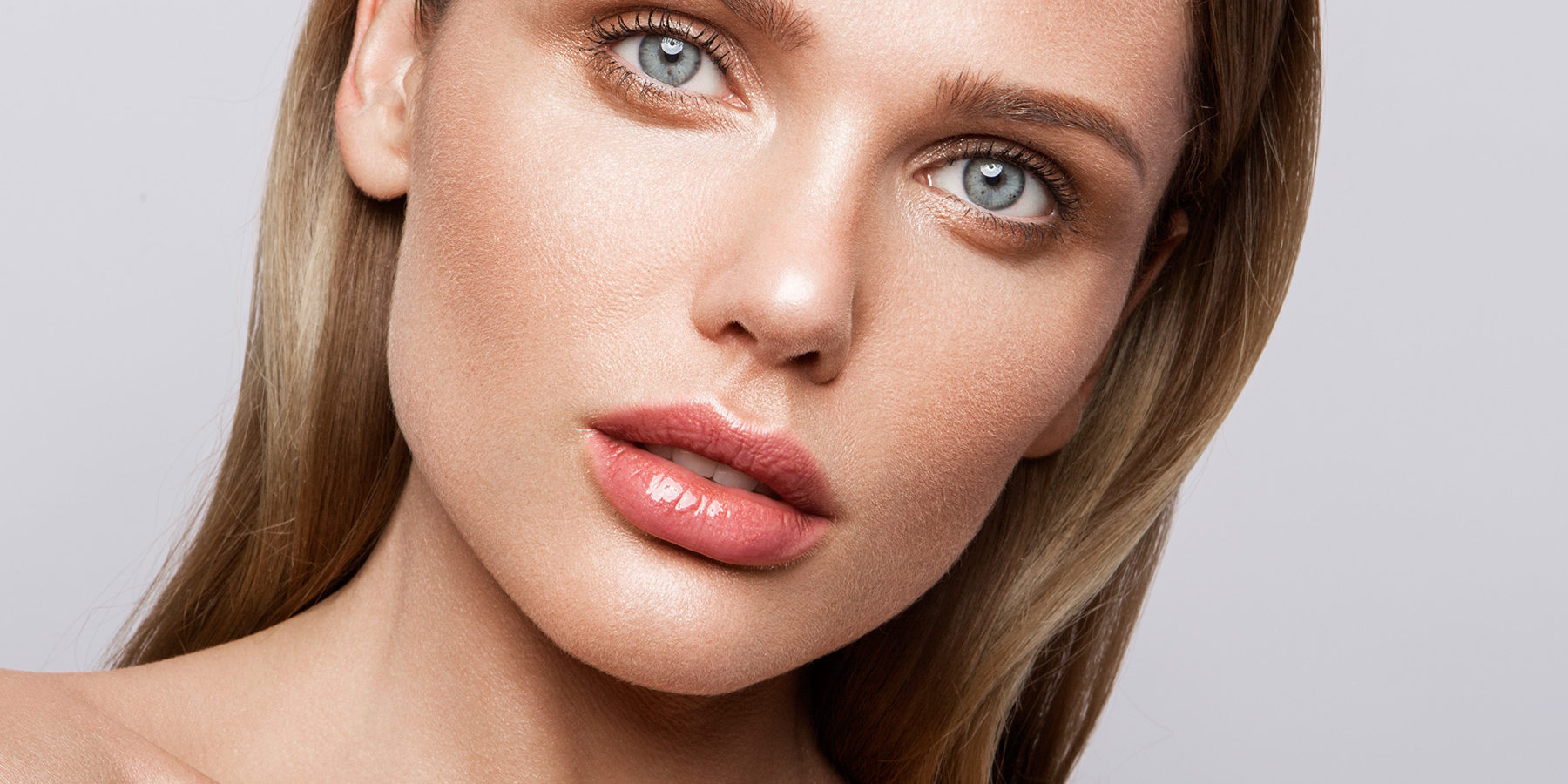 Beauty portrait of model with natural make-up. Fashion shiny highlighter on skin, sexy gloss lips make-up
